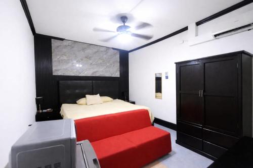 a bedroom with a bed with a red couch and a tv at Hotel Garcias Suites, Linares in Linares