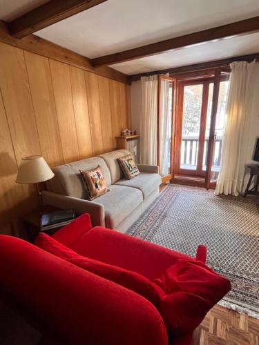 a living room with a red couch and a window at La casa di Marta, charme e relax in Breuil-Cervinia