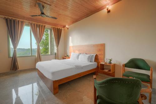 a bedroom with a bed and a green chair at Hotel Sarai Bharatgarh in Nohan