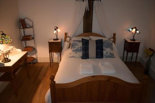 a bedroom with a large wooden bed with two lamps at Séminaire Comme à la Maison - cosy, écossais & productif en Sologne in Aubigny-sur-Nère