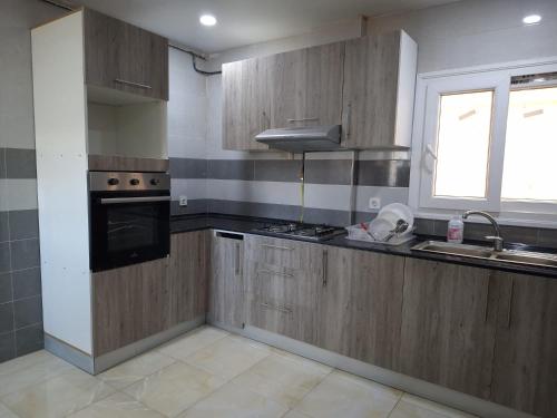 una cucina con mobili in legno, un lavandino e una finestra di Appartements Mimosa a Tefeschoun