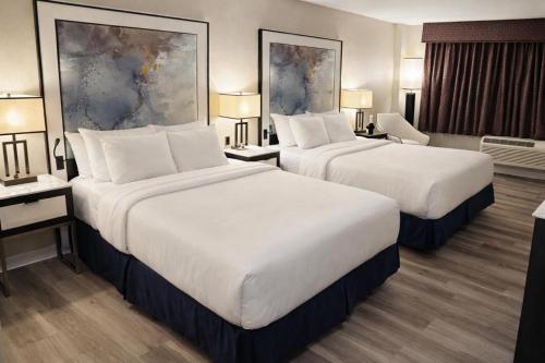two beds in a hotel room with two lamps at Nova Hotel Bronx in Melrose