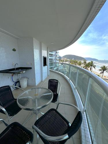 a balcony with a table and chairs and the ocean at Apt com vista para o mar e churrasqueira in Guaratuba