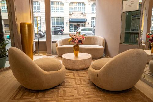 a lobby with two chairs and a table with a vase of flowers at Adrett Hotel Königsallee in Düsseldorf