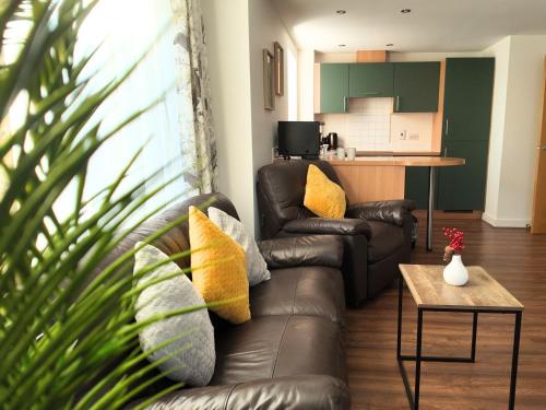 a living room with a leather couch and a table at Luxury Spacious Apartment- Sleeps 4 Loughborough in Loughborough