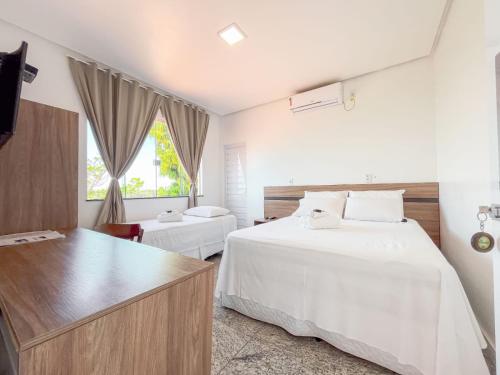 a hotel room with two beds and a dresser at Pousada Barreirinhas in Barreirinhas