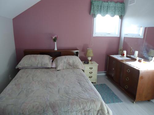 een slaapkamer met een bed, een dressoir en een raam bij Domaine sur une plage in Saint-Félicien