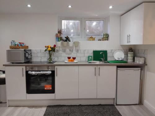 a kitchen with white cabinets and a counter top at Cosy studio flat with free wifi and free parking in Killingbeck