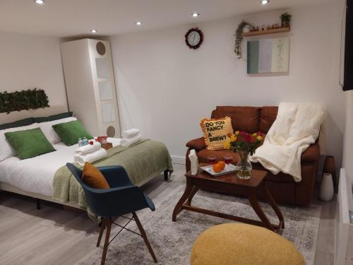 a bedroom with a bed and a couch and a table at Cosy studio flat with free wifi and free parking in Killingbeck