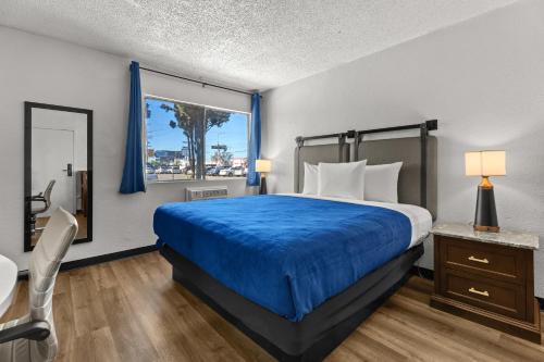 a bedroom with a bed with a blue bedspread and a window at Studio Lodge Hotel in Hewitt