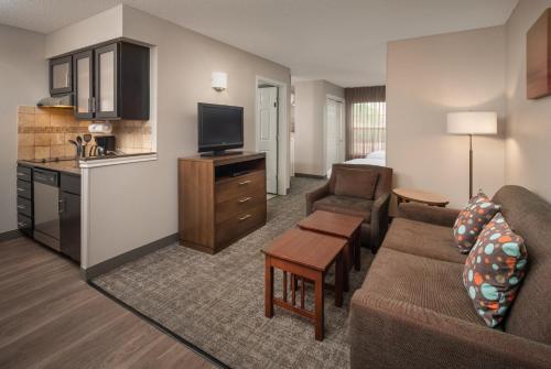 a living room with a couch and a tv and a kitchen at Staybridge Suites Denver Tech Center by IHG in Centennial