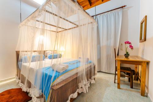 a bedroom with a canopy bed with a desk at The One Hikkaduwa in Hikkaduwa