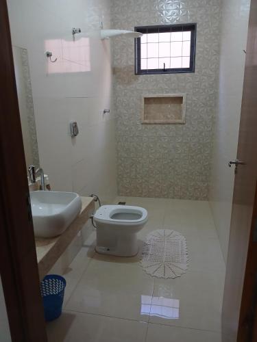 a bathroom with a toilet and a sink and a window at Quartos Festa do Peão Barretos in Barretos