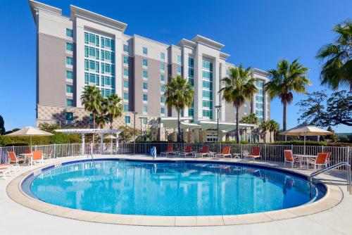 a swimming pool in front of a hotel with palm trees at Hampton Inn & Suites Tampa Airport Avion Park Westshore in Tampa
