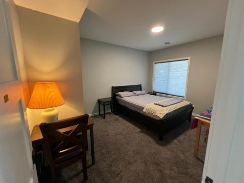 a bedroom with a bed and a lamp and a chair at Pond view Walkout in Airdrie