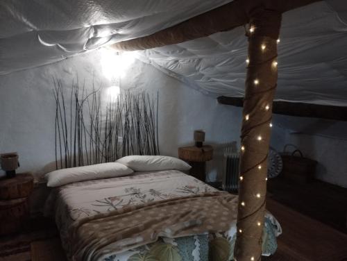 a bedroom with a canopy bed with lights on it at Winahost Casita Sierra de Madrid in Las Herreras