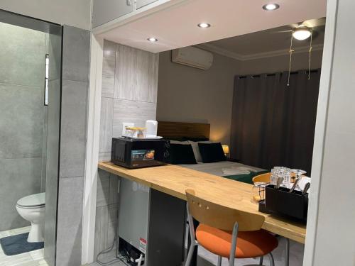 a room with a desk with a microwave and a bed at Luigi's Place in Pretoria