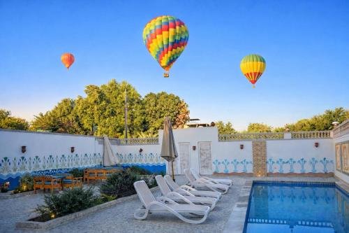 two hot air balloons flying over a swimming pool at Astralis Hotel - Hot Air Balloon View in Al Aqālitah