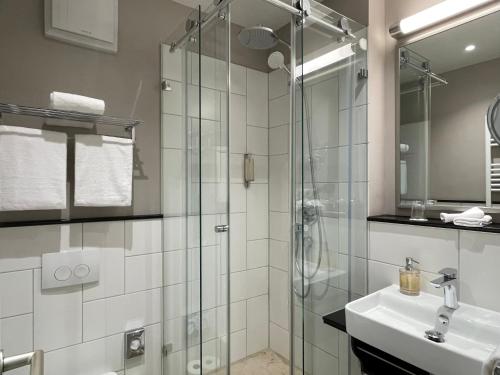 a bathroom with a glass shower and a sink at Jugendstilhotel Trifels in Annweiler am Trifels