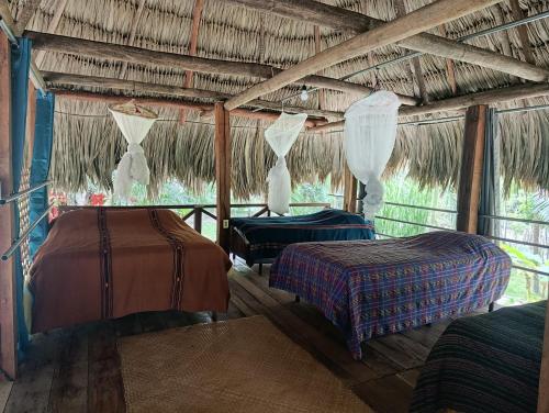 a room with two beds and a thatched roof at Alice Guesthouse in El Remate