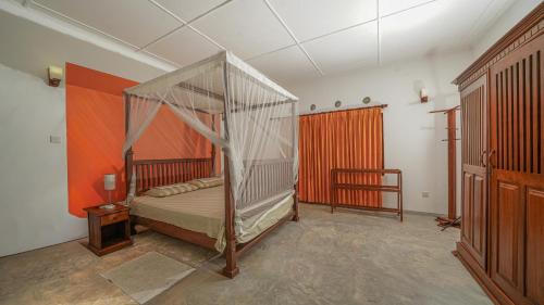 a bedroom with a canopy bed and an orange curtain at GalleRetreat in Galle