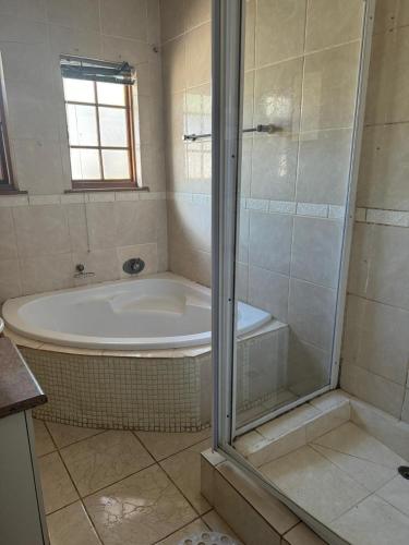 a bathroom with a shower and a bath tub at Tana B Guesthouse in Welkom