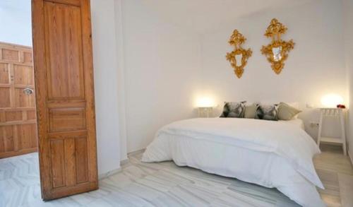 セビリアにあるApartamentos Almirante Hoyosの白いベッドと木製のドアが備わるベッドルーム1室が備わります。