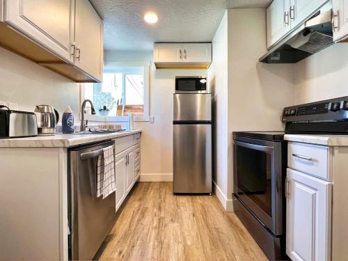 a kitchen with stainless steel appliances and wooden floors at Sun & Snow Bungalow Remodeled Hot Tub W&D in South Salt Lake