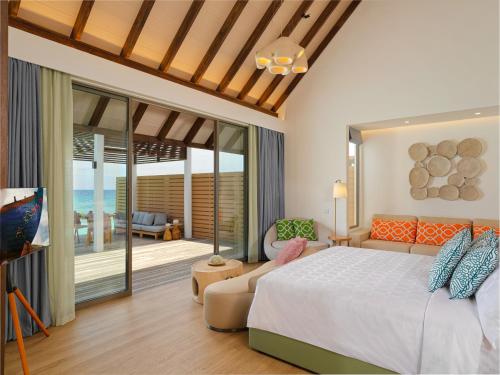 a bedroom with a bed and a living room at Meyyafushi Maldives - Premium All Inclusive in Lhaviyani Atoll