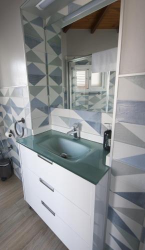 a bathroom with a green sink and a mirror at Apartamentos turísticos ilusiones in Cazalla de la Sierra