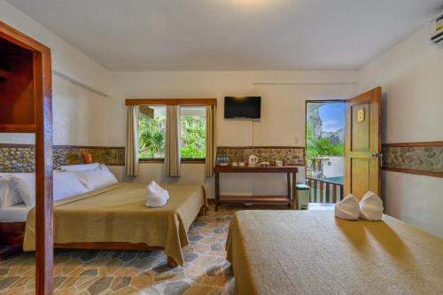 a bedroom with two beds and a desk and windows at El Nido Viewdeck Cottages in El Nido