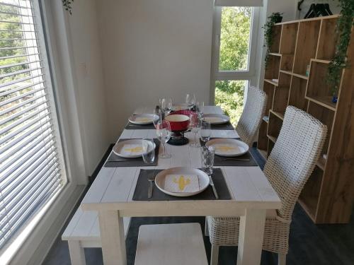a wooden table with plates and wine glasses on it at Loft lumineux et confortable in Grimisuat