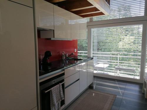 a kitchen with white cabinets and a large window at Loft lumineux et confortable in Grimisuat