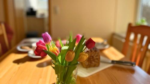 a vase filled with flowers on a wooden table at Bauernhuus 6 in Fehmarn