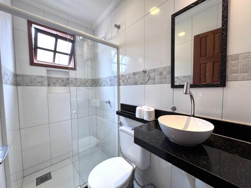 a bathroom with a sink and a toilet and a mirror at FLAT Estalagem 11 in Arraial do Cabo