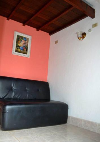 a black couch in a room with a red wall at Pousada Em Busca do Sol in Trindade