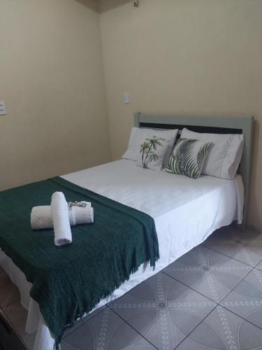 a bed with two pillows and a green blanket at Residence tropical, disponível 2 quartos para alugar in Guriú