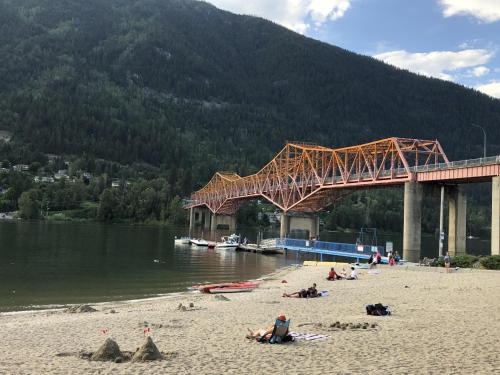 people on a beach with a bridge and a mountain at Boho Bungalow in Nelson
