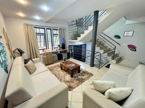 a living room with white furniture and a staircase at GoHost Suítes - 2 Ruas do Shopping Santa Úrsula in Ribeirão Preto