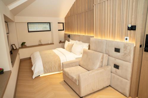 a large bedroom with a bed and a chair at Post Inn Hotel-New Bazaar in Tirana