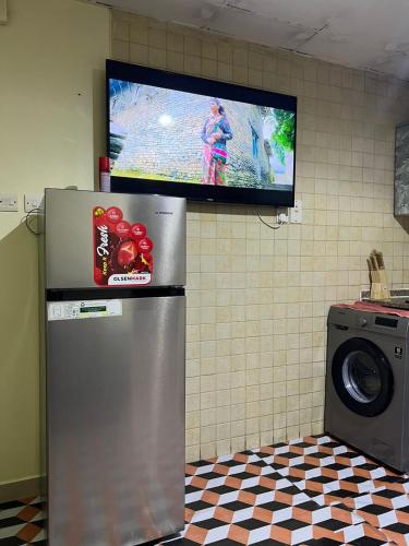 a television hanging on a wall with a refrigerator at ALFUTTAIN Vacation Homes Rental in Dubai