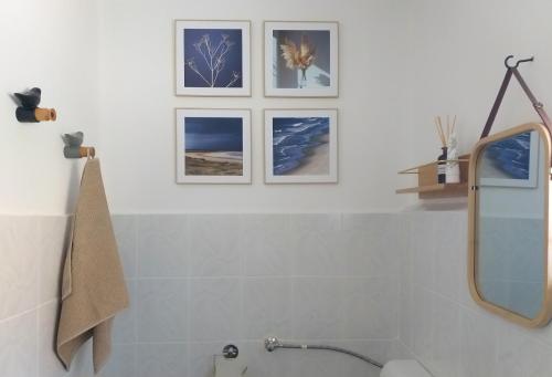 a bathroom with three pictures on the wall at Arany Virág Vendégház in Mór