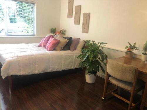 a bedroom with a bed with pillows and a table at Quiet-comfy 3 bedroom house on a tree lined street in Kitsilano in Vancouver