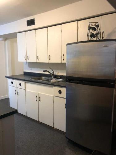 a kitchen with a stainless steel refrigerator and white cabinets at Quiet-comfy 3 bedroom house on a tree lined street in Kitsilano in Vancouver