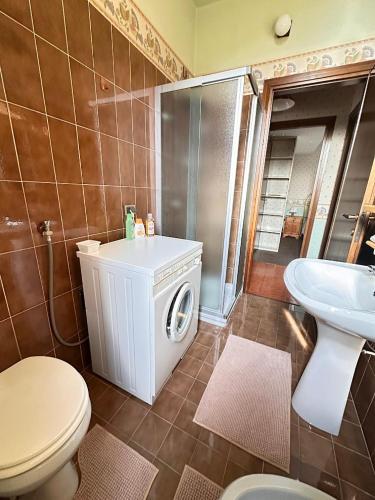 a bathroom with a toilet a sink and a washing machine at Casa di David in Cerete