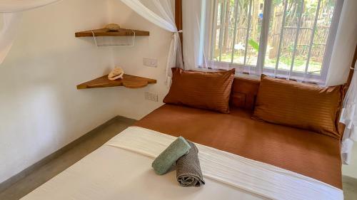 a small room with a bed with a window at Jungle Cottage in Tangalle