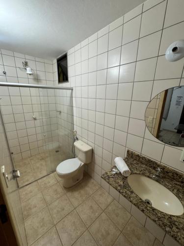 a bathroom with a toilet and a sink and a mirror at Pousada Refúgio da Ilha in São Mateus