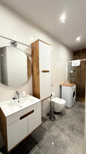a bathroom with a sink and a toilet and a mirror at MICKIEWICZ HOUSE Apartamenty in Wadowice