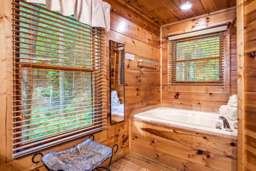 a log cabin bathroom with a tub and a window at A Bear's view in Sevierville