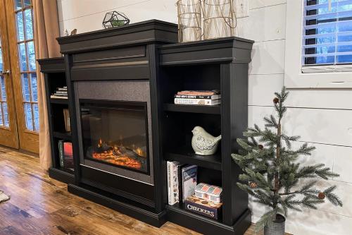 a black fireplace in a living room with a christmas tree at Modern Pond-View Cabin Near Lake of Egypt in Marion